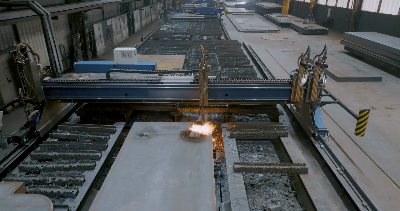 Automatisierte Brennschneidmaschine schneidet eine dicke Stahlplatte in einer Industriehalle mit hellem Funkenflug