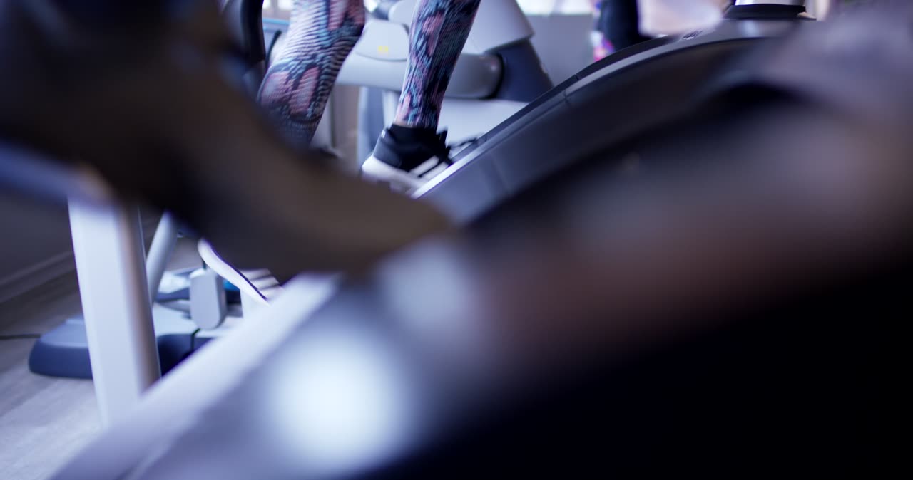 Beine einer Person in gemusterten Leggings beim Training auf einem Fitnessgerät im Studio