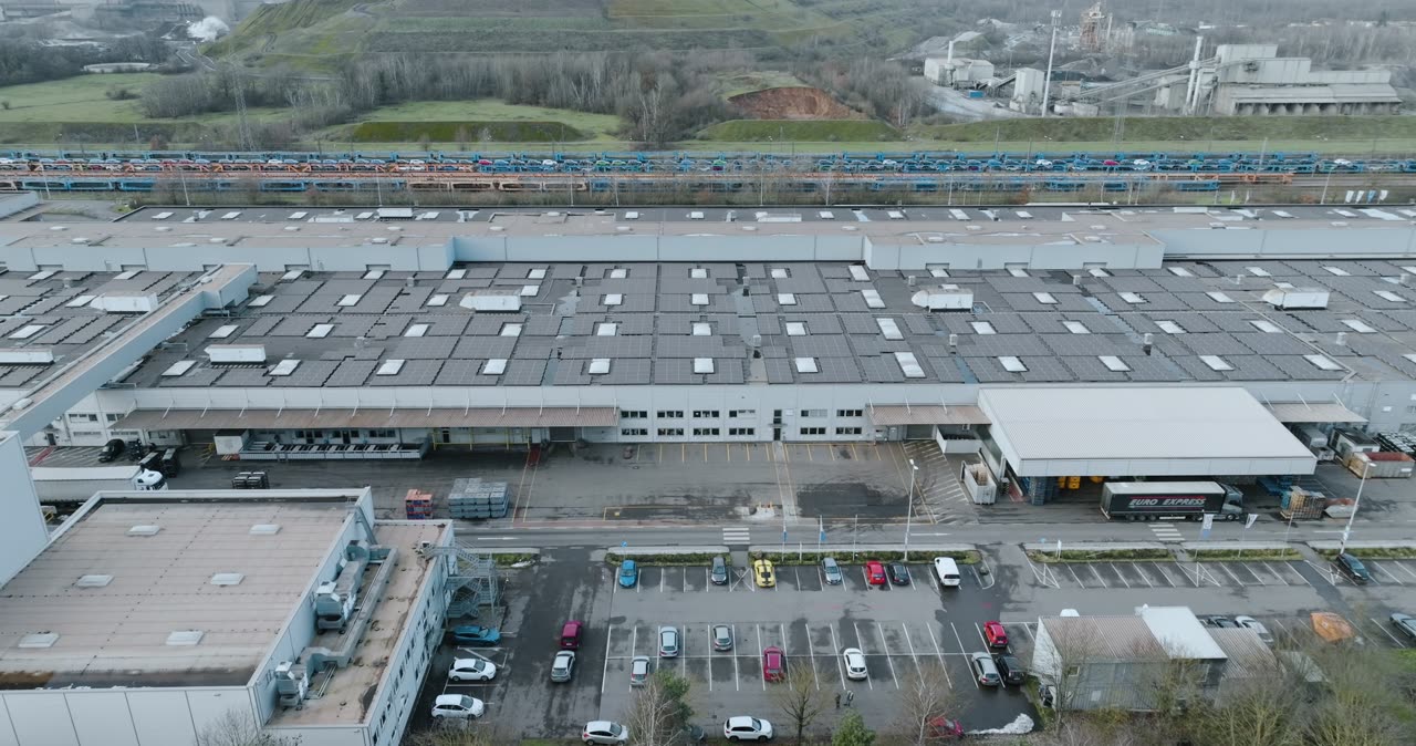 Drohnenaufnahme von einer großen Industriehalle mit Photovoltaikanlage auf dem Dach