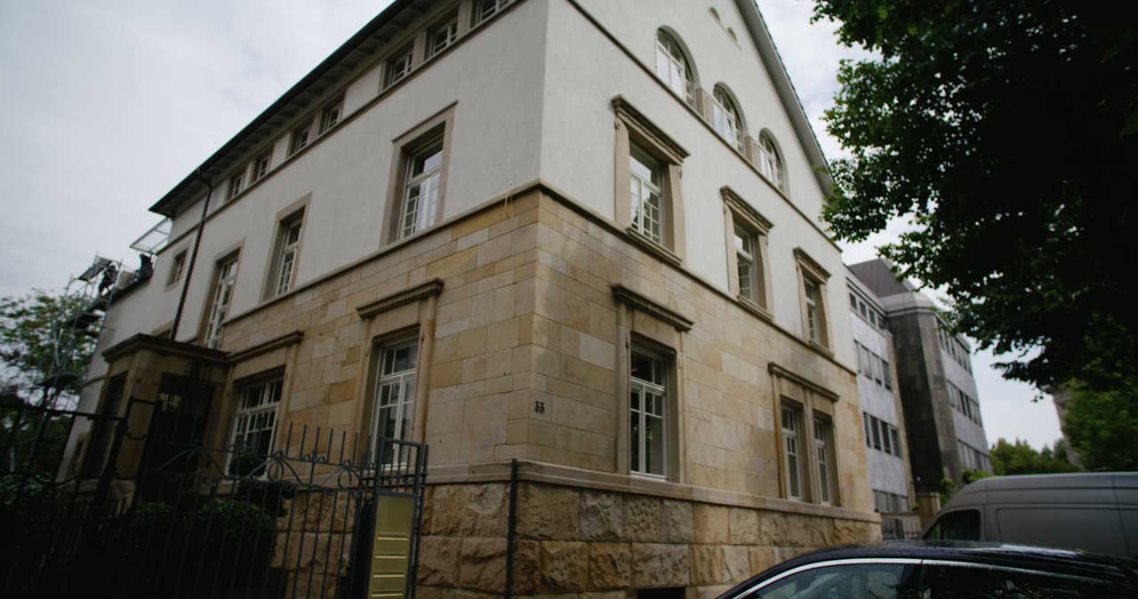 Froschperspektive von einem mehrstöckigen Wohnhaus mit Sandsteinfassade und weißem Putz an einer Straße