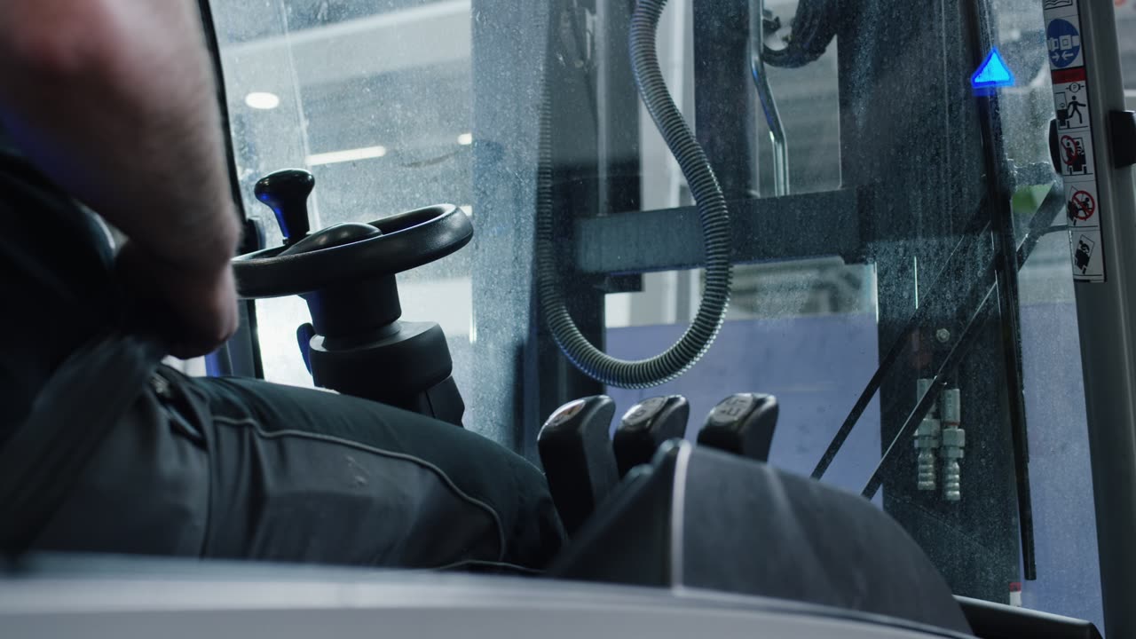 Gabelstaplerfahrer bedient Hydraulikhebel im Führerhaus einer industriellen Zugmaschine