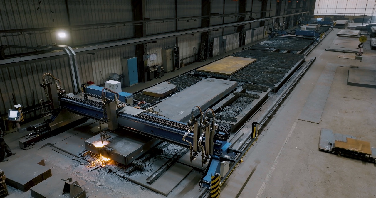 Große CNC-Brennschneidanlage bei der automatisierten Bearbeitung von massiven Stahlplatten in einer Werkhalle