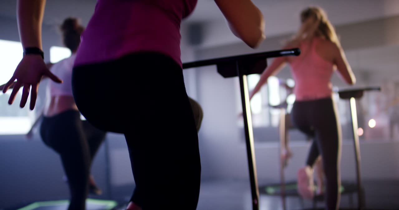 Gruppe von Frauen beim synchronen Fitnesstraining auf kleinen Trampolinen im Studio