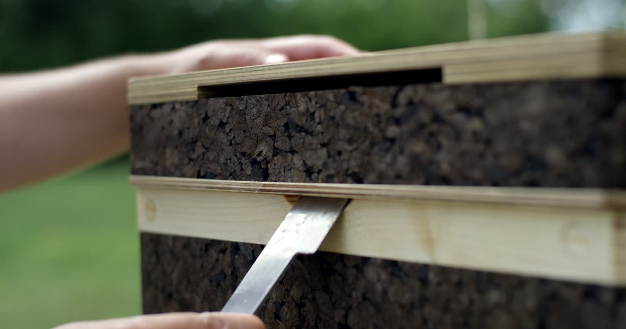 Imker öffnet einen Bienenstock aus Kork mit einem Stockmeißel