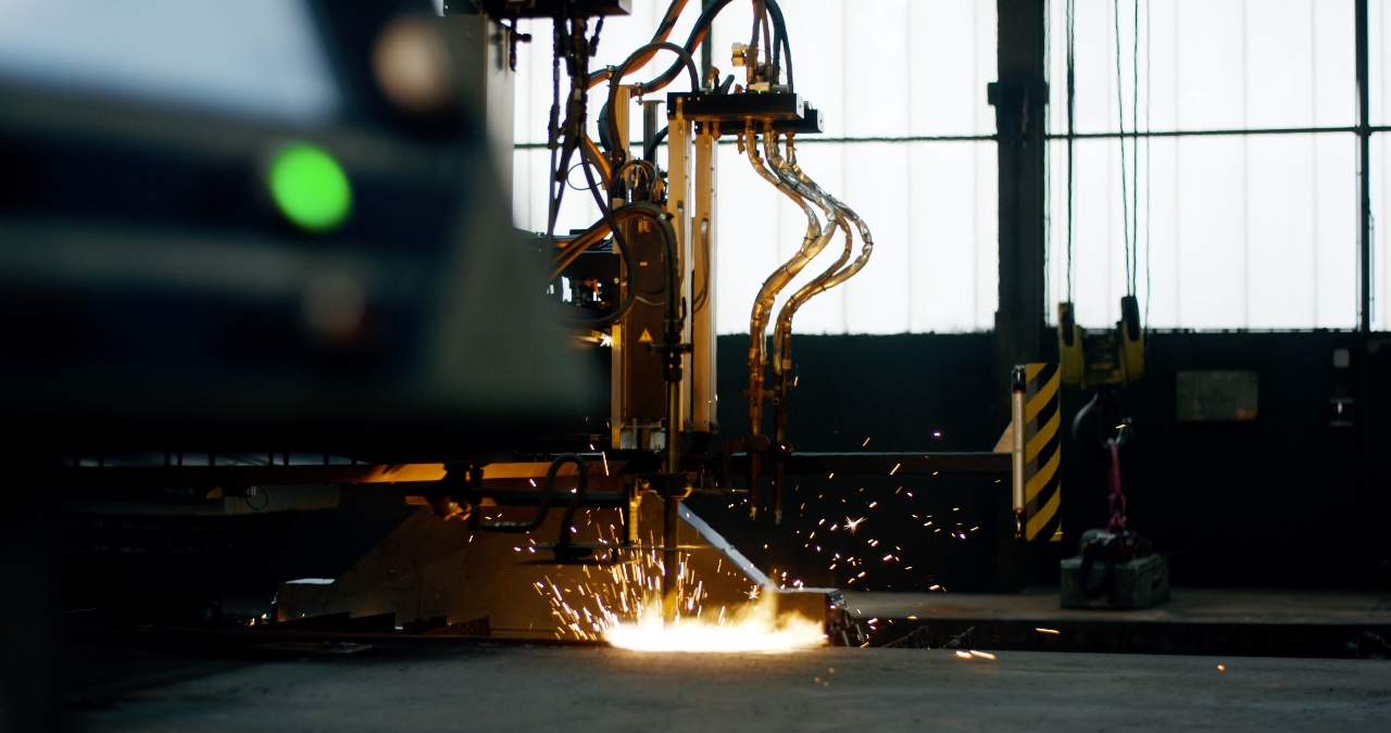 Industrielle Brennschneidmaschine im Einsatz beim thermischen Trennen einer Metallplatte mit hellem Lichtbogen