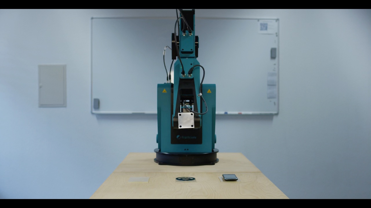 Industrieller Gelenkarmroboter auf Holztisch führt präzise Drehbewegungen in einem hellen Laborraum vor Whiteboard aus