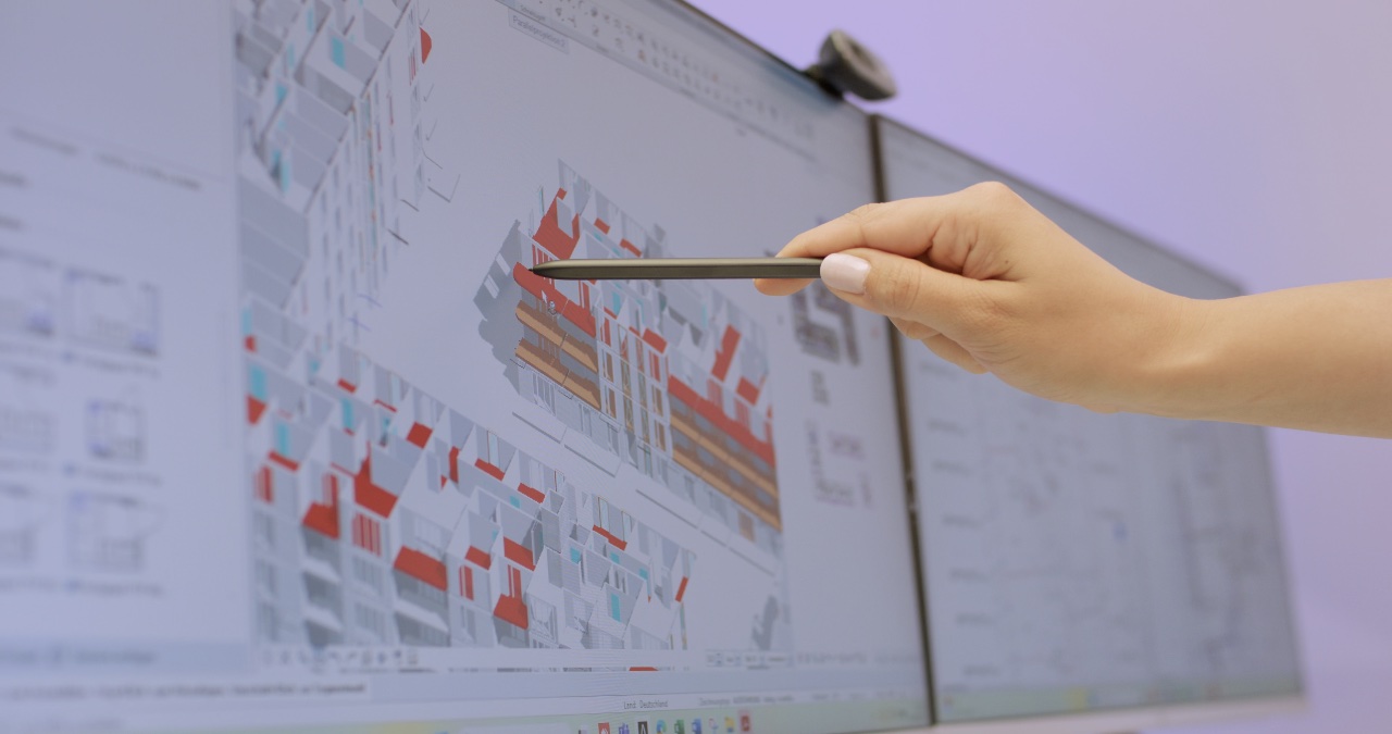 Ingenieurin erläutert eine komplexe 3D-CAD-Planung für ein Gebäudeprojekt am Bildschirm