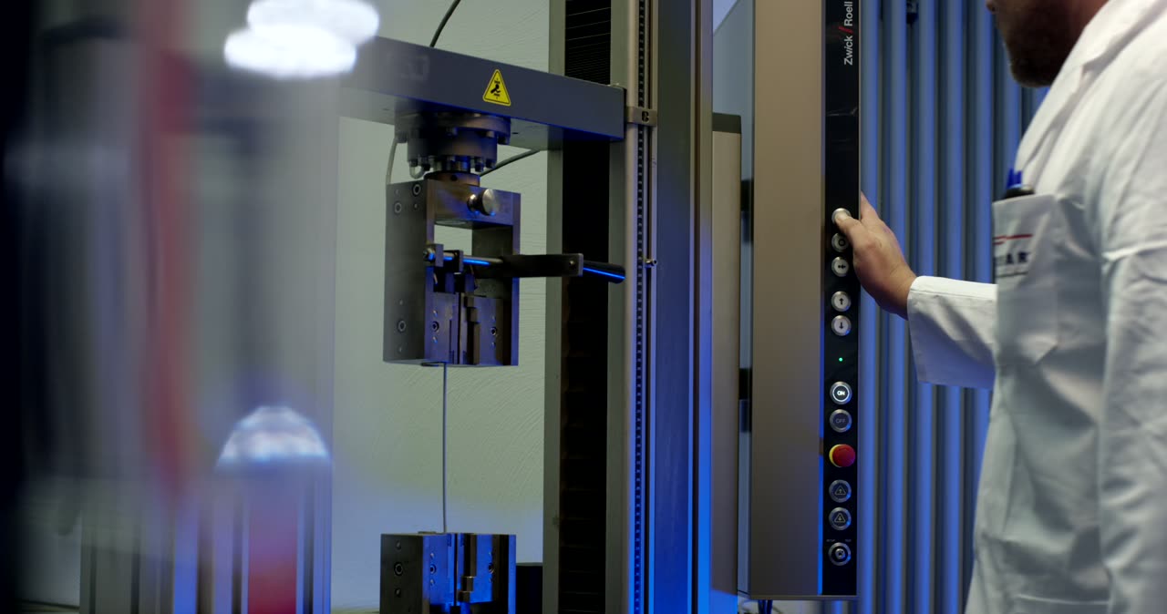 Mitarbeiter der Qualitätssicherung bedient eine ZwickRoell Zugprüfmaschine im Labor
