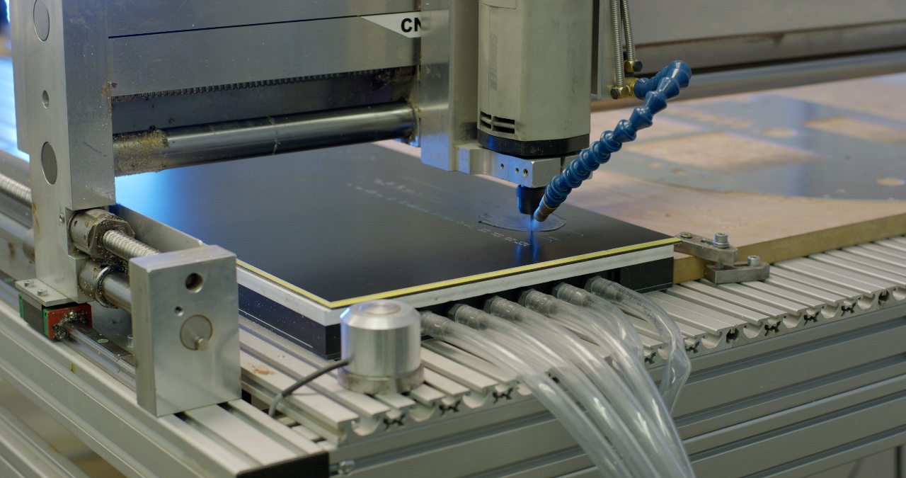 Moderne CNC-Fräse bei der präzisen Bearbeitung einer dunklen Kunststoffplatte in einer industriellen Fertigung