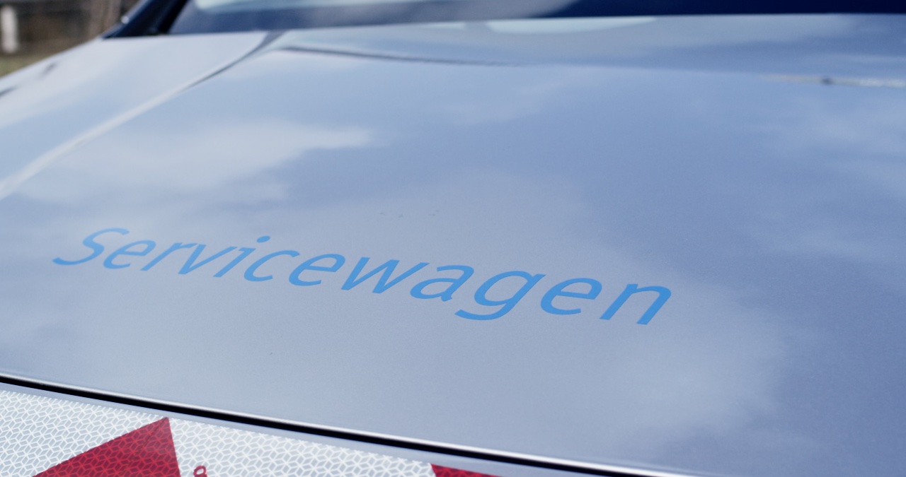 Nahaufnahme der Motorhaube eines silbernen Servicefahrzeugs mit blauem  Servicewagen -Schriftzug