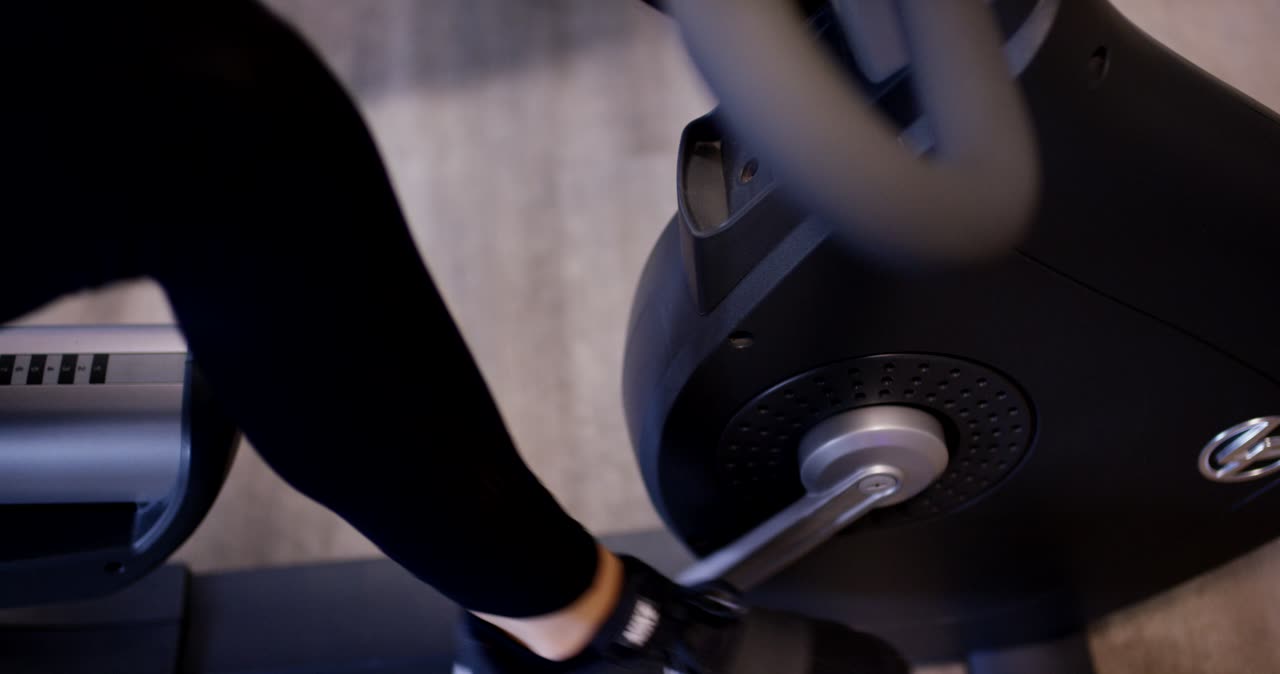 Person beim Ausdauertraining auf einem stationären Fahrradergometer im Fitnessstudio