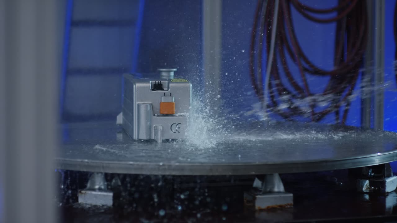 Silberner Lithium-Ionen-Akku bei einem Spritzwasser-Belastungstest auf einem rotierenden Drehteller