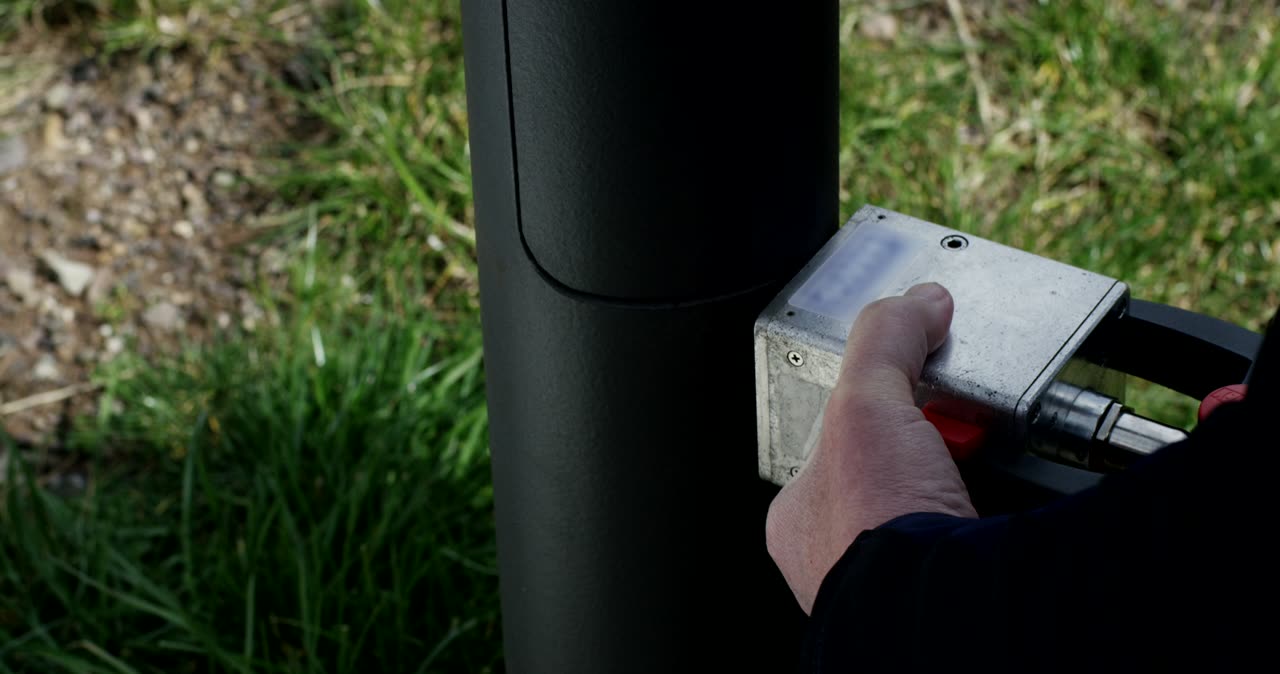 Techniker prüft die Materialbeschaffenheit eines Lichtmasts mit einem Messgerät