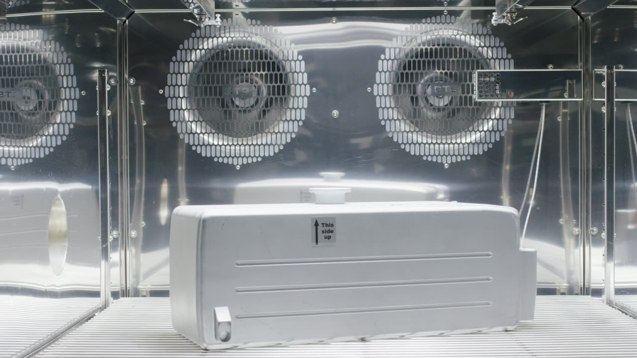Weisser Behaelter im Inneren einer technischen Pruefkammer aus Edelstahl mit Ventilatoren