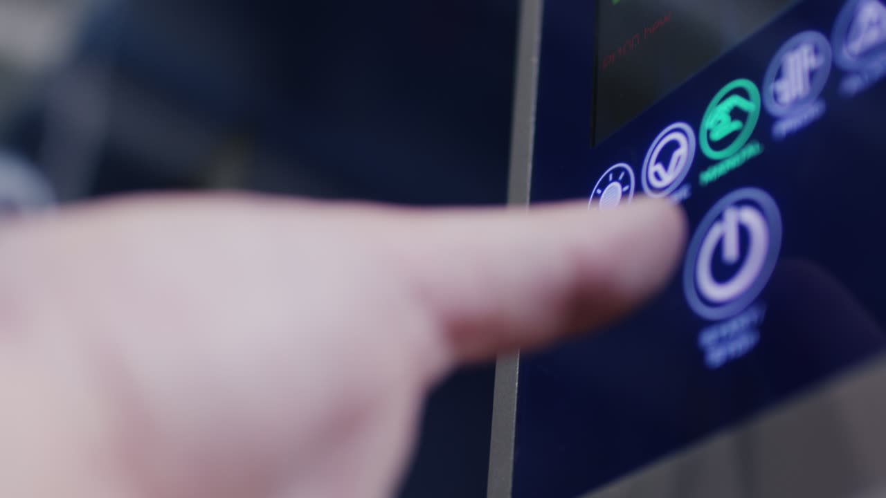 Zeigefinger drueckt die beleuchtete Start und Stop Taste auf einem blauen Bedienfeld